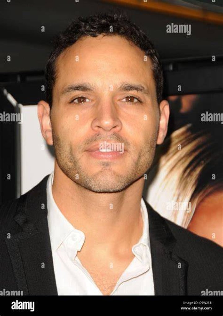 Daniel Sunjata in a white shirt and black suit.